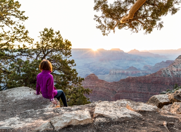 Tourist Is Seating On The Edge of Cliff and Watching of Sunrise at Grand Canyon from Mather Point